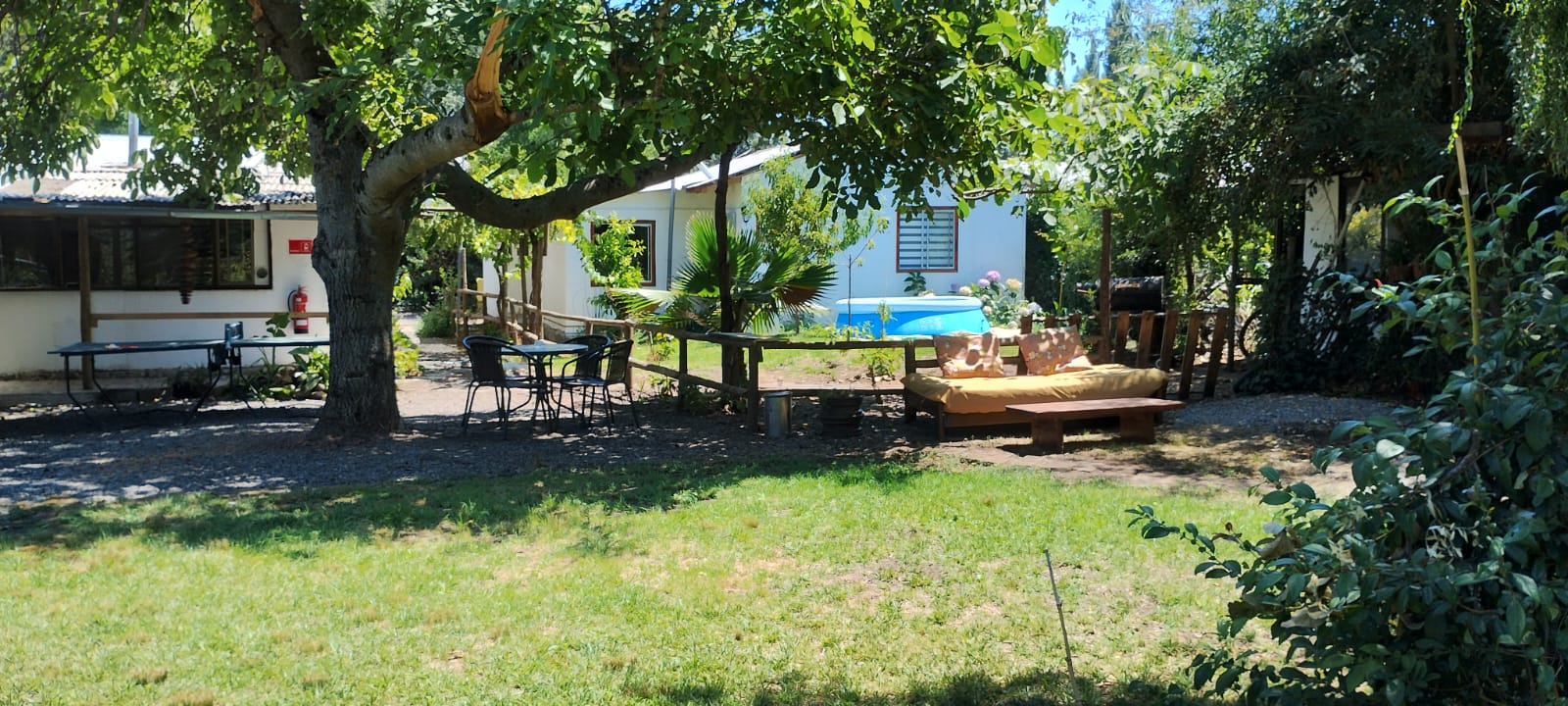 Patio con pasto, árboles grandes y espacios de descanso en Mi Refugio en el Campo